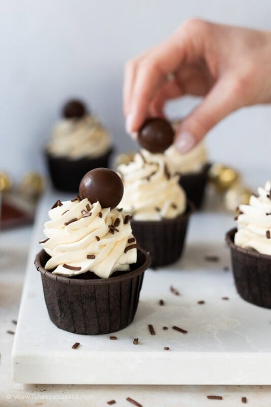 Placing a baileys truffle on a baileys cupcake
