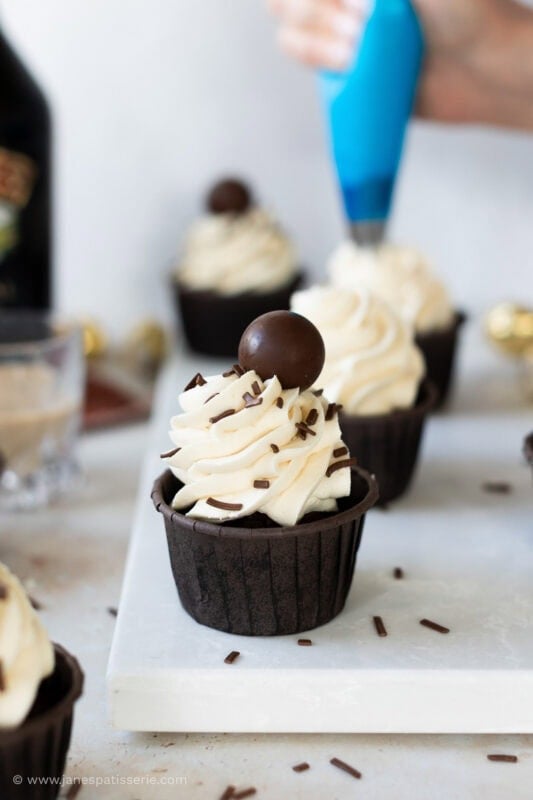Baileys cupcakes being piped with Baileys buttercream