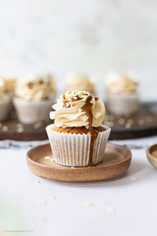 A wider shot of a butterscotch cupcake on a plate
