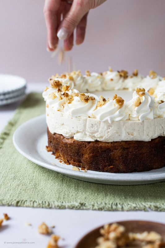 A hand decorating a carrot cake cheesecake