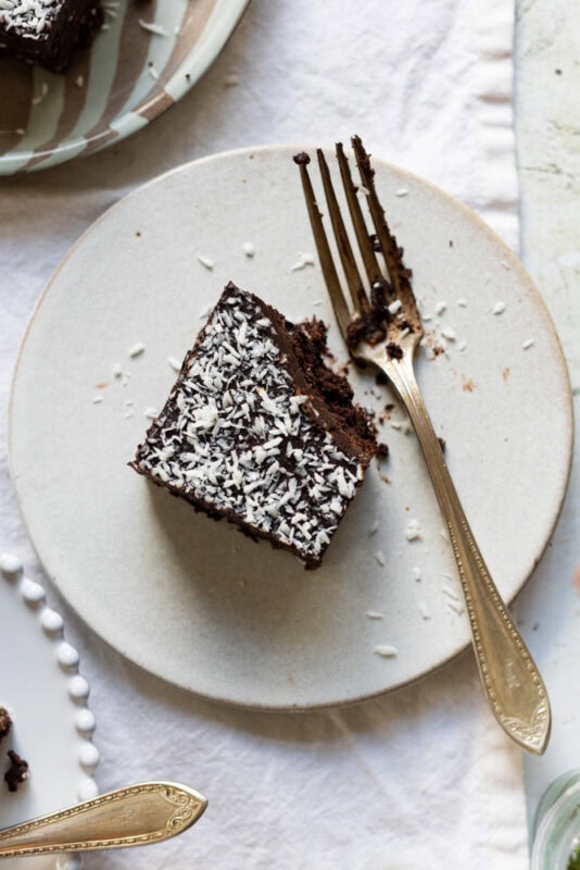 A plate with a coconut brownie with a bite missing