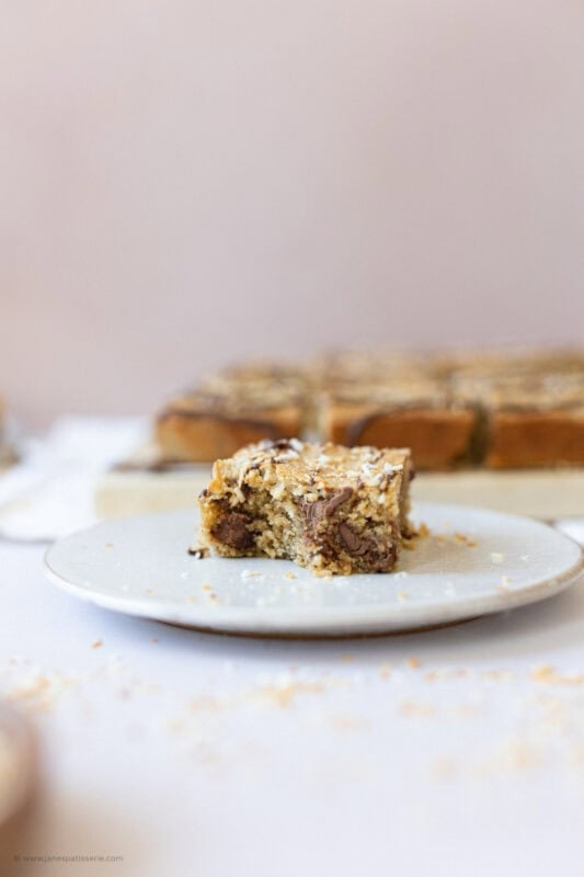 A single Coconut Chocolate Blondie on a white plate