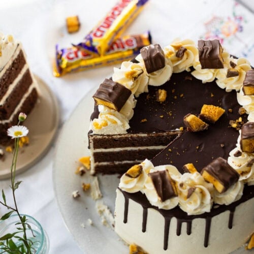 A slice missing of a crunchie drip cake with crunchies