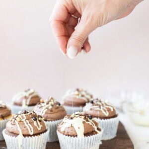 a hand putting sprinkles on a marble cupcake