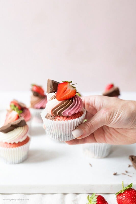 A hand holding a finished Neapolitan Cupcake