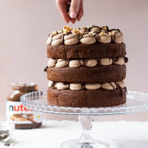 A hand decorating a Nutella Cake