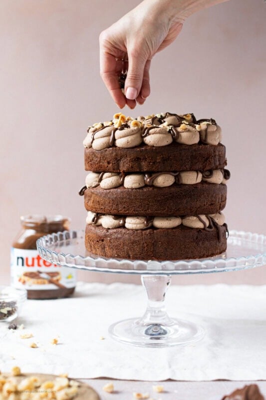 A hand decorating a Nutella Cake