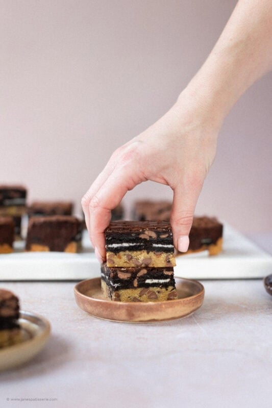 A hand taking a Slutty Brownie from a plate