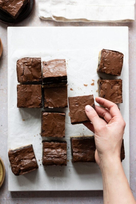 A hand taking a Slutty Brownie from the tray