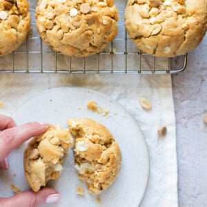 A hand reaching for a Peanut Butter NYC Cookie