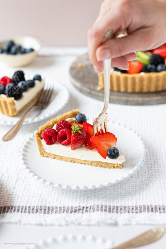 A fork picking up fruit from the top of a slice of Easy Fruit Tart