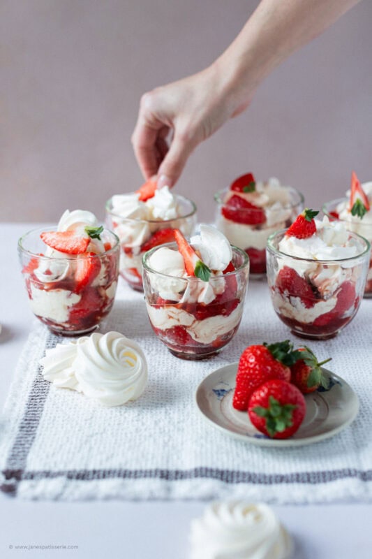 A hand decorating a Eton mess with Homemade meringues.