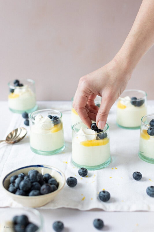A hand decorating a jar of Lemon Curd Mousse