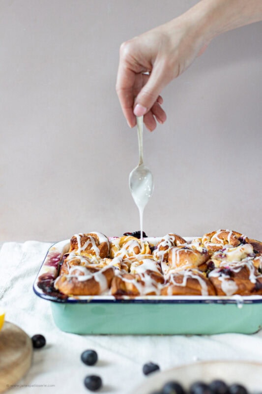 Side angle of icing decorating lemon and blueberry rolls