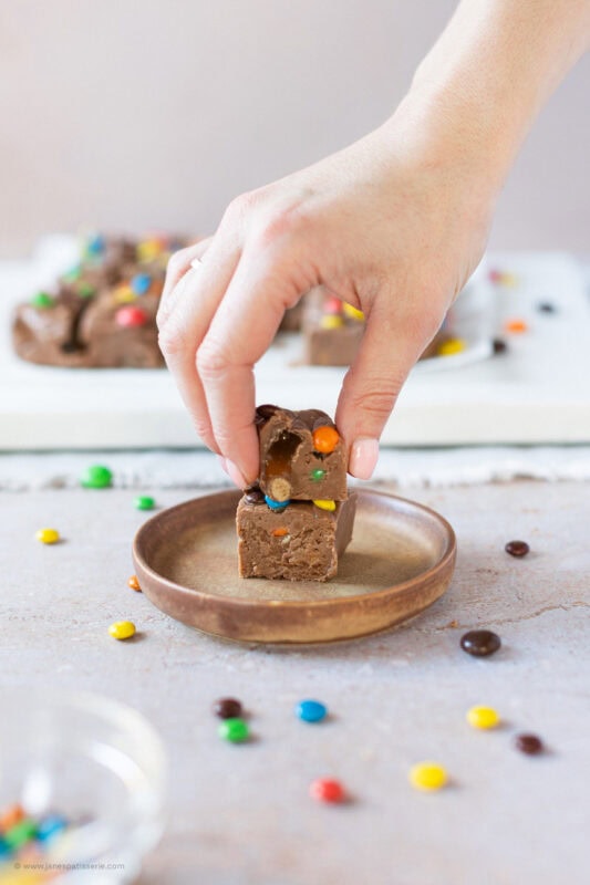 A hand taking one of two slices of microwave fudge from a plate