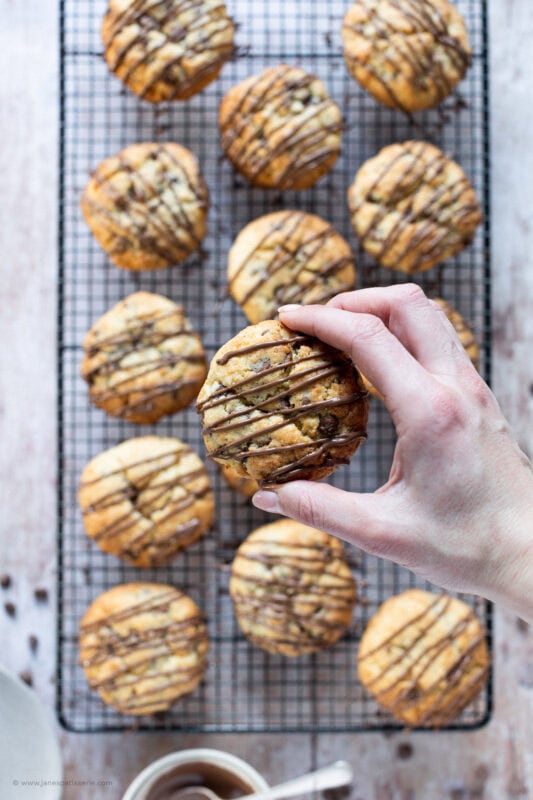 A hand taking a Coconut Chocolate Rock from a cooling rack batch