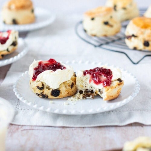 A bite taken from a Fruit Scone with jam and clotted cream