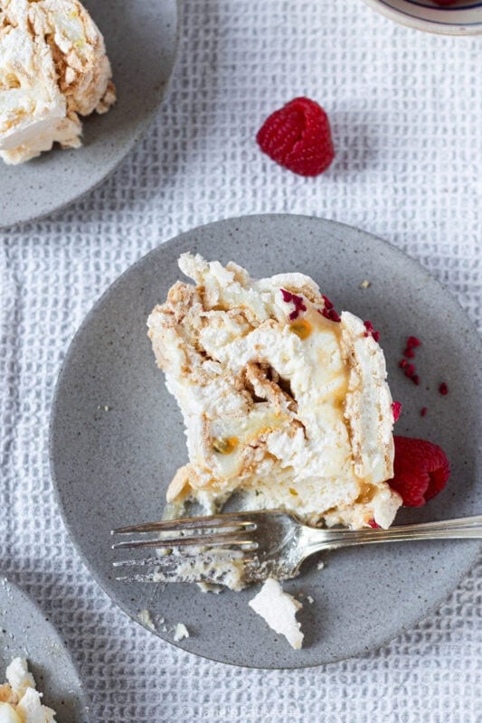 A slice of lemon meringue roulade on a plate with a fork