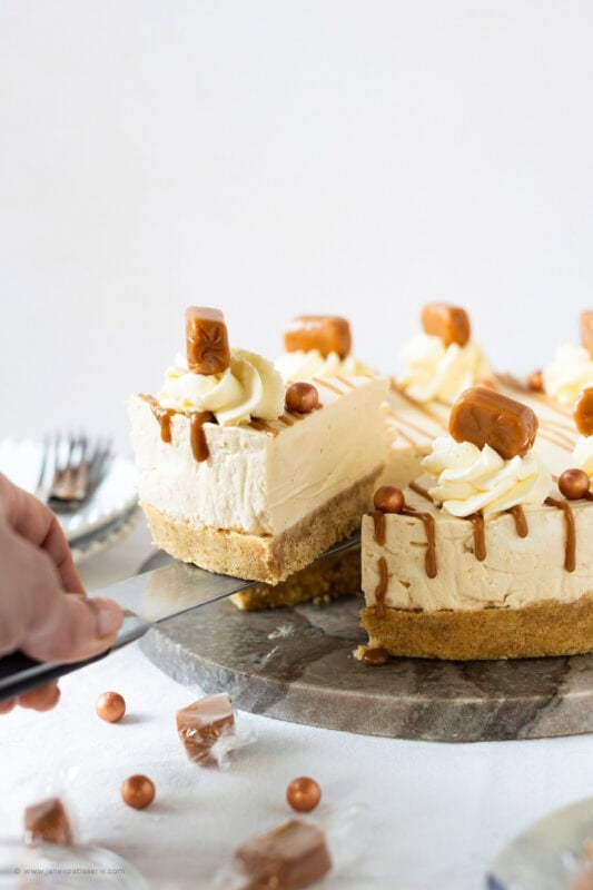 A slice being removed from a whole Butterscotch cheesecake