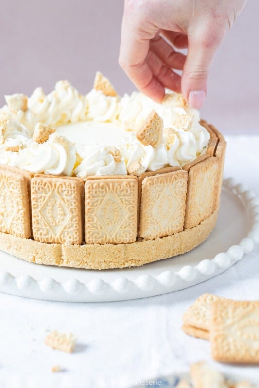 A hand decorating a custard cream cheesecake