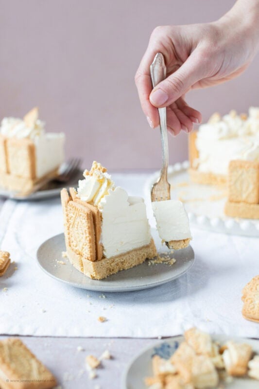 A fork taking a bite from a Custard cream cheesecake slice