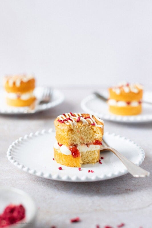 A bite missing from a mini Victoria sponge cake on a plate