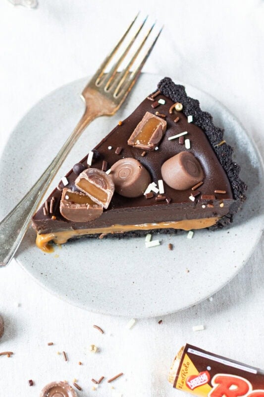 A slice of no-bake Rolo tart on a plate with a fork