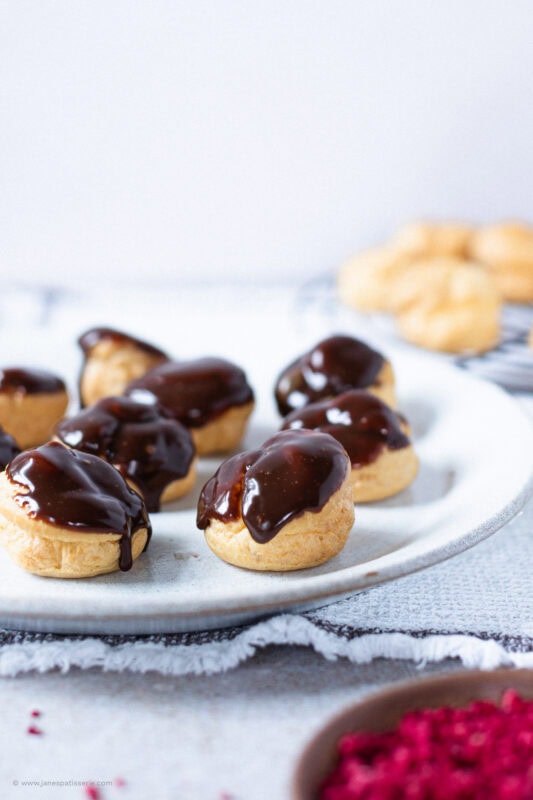 A plate of unfinished profiteroles waiting to be decorated