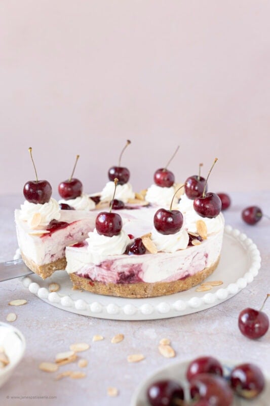 A slice being removed from a whole Cherry Bakewell Cheesecake