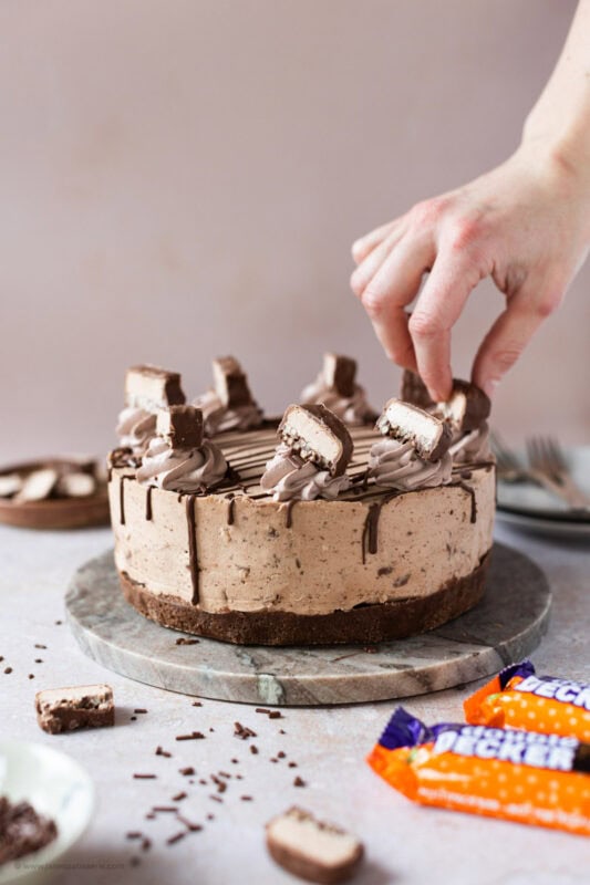 A hand placing the final decorative touches to a Double Decker Cheesecake
