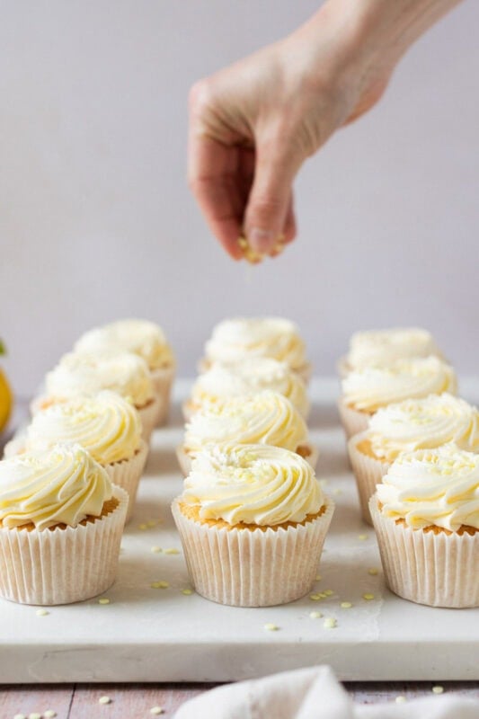 A hand decorating finished Lemon Drizzle Cupcakes