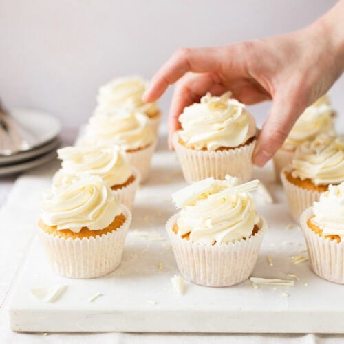 A hand taking a White Chocolate Cupcake