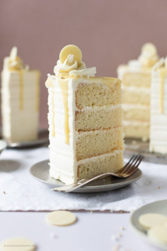 A slice of White chocolate drip cake on a grey plate