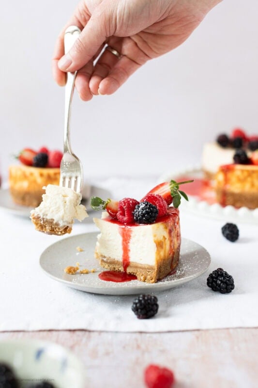 A fork taking a single bite from a slice of New York Cheesecake