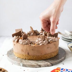 A hand decorating a no-bake daim cheesecake